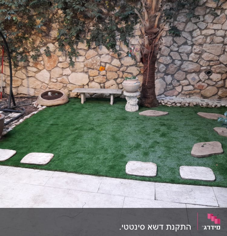 דשא סינתטי עם אבנים ועציצים בגינה קטנה